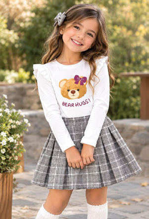 Niña con blusa blanca de osito y falda plisada a cuadros gris