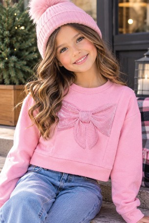 Niña con gorro tejido rosa y sudadera rosa con moño aplicado